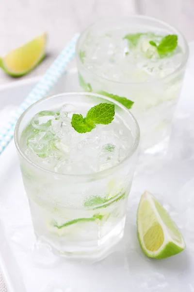 Cóctel de mojito frío sin alcohol con limón fresco, menta y hielo picado en un plato blanco — Foto de Stock