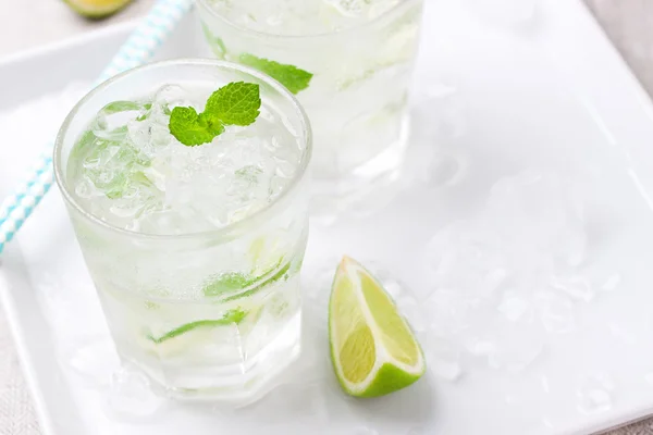 Cocktail de mojito froid sans alcool avec citron vert frais, menthe et glace concassée sur une assiette blanche — Photo