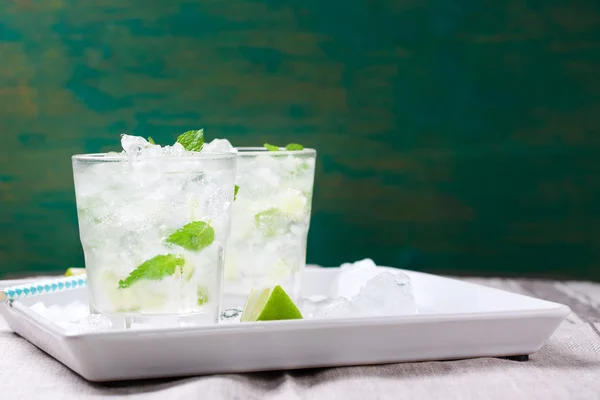 Cocktail de mojito froid sans alcool avec citron vert frais, menthe et glace concassée sur une assiette blanche — Photo