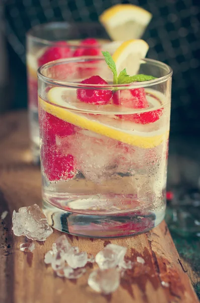 Homemade summer cold raspberry lemon cocktail with sparkling water and crushed iced in glasses on a vintage background — Stock Photo, Image