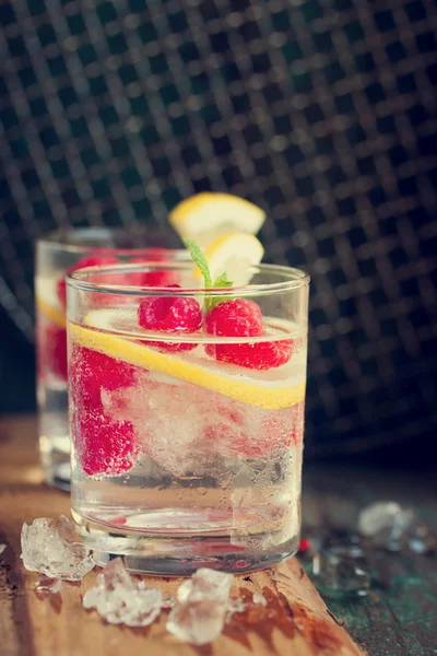 Cocktail maison au citron framboise froid d'été avec eau pétillante et glace concassée dans des verres sur un fond vintage — Photo