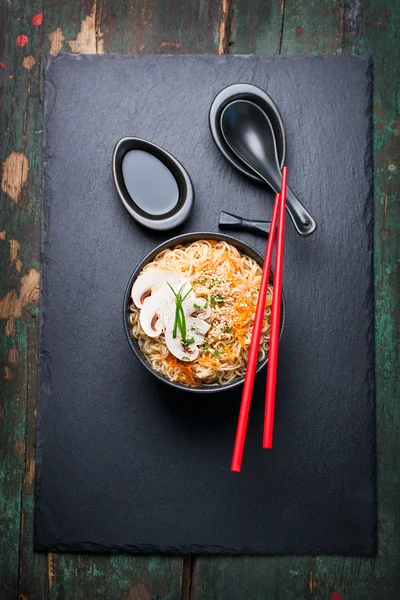 Fideos asiáticos con verduras y champiñones, salsa de soja, palos sobre un fondo oscuro, vista superior con espacio para copiar —  Fotos de Stock