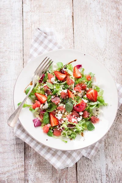 Sommar sallad med grapefrukt, jordgubb, mint, balsamvinäger och ost på en plåt på en trä bakgrund, närbild — Stockfoto