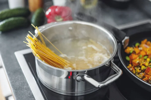 キッチンでスパゲティパスタを調理して鍋を沸かします — ストック写真