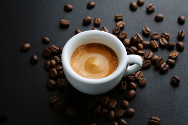 Kahve çekirdekleri ve kaşıkla servis edilen lezzetli espresso. - Yakın çekim. Koyu arkaplan. 