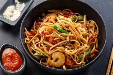 Karides ve sebzeli Asya erişteleri koyu arka planda kasede servis edilir.. 