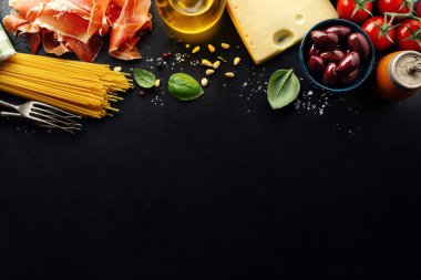 Geleneksel İtalyan yemekleri arka planında spagetti domates peyniri zeytin ve koyu arkaplanda yağ.. 