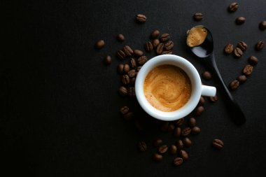 Kahve çekirdekleri ve kaşıkla servis edilen lezzetli espresso. Yukarıdan bak. Koyu arkaplan. 