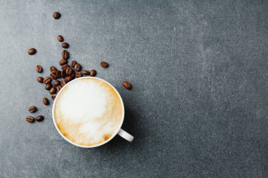 Lezzetli, iştah açıcı kapuçino bardakta, somut arkaplanda fasulye.. 