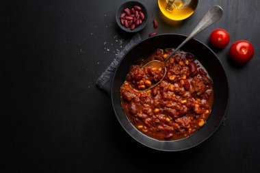 Koyu arkaplanda yemek için klozette servis edilen chili con carne. 
