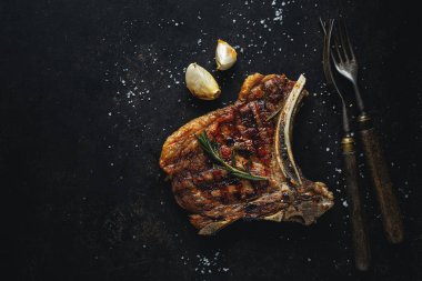 Baharatlı ızgara biftek ve siyah arka planda çatal bıçak takımı. Üst Görünüm
