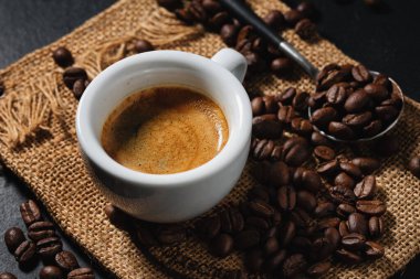 Kahve çekirdekleri ve kaşıkla servis edilen lezzetli espresso. - Yakın çekim. Koyu arkaplan. 