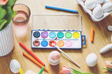 Ahşap masa üzerinde yumurta ve çiçek boyama araçları ile Paskalya yaşam tarzı. Yukarıdan görüntüle. 