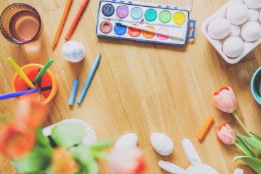 Ahşap masa üzerinde yumurta ve çiçek boyama araçları ile Paskalya yaşam tarzı. Yukarıdan görüntüle. 