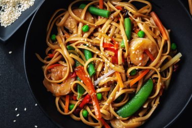 Karides ve sebzeli Asya erişteleri koyu arka planda kasede servis edilir.. 