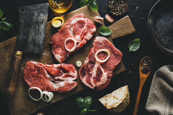 Raw meat on board with spices and herbs on board on dark background. Top View. 