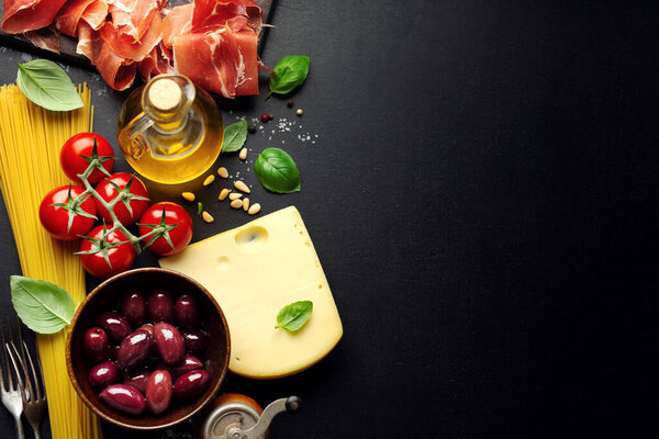 Traditional italian food background with spaghetti tomatoes cheese olives and oil on dark background. 