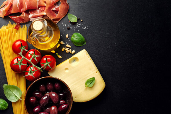Traditional italian food background with spaghetti tomatoes cheese olives and oil on dark background. 