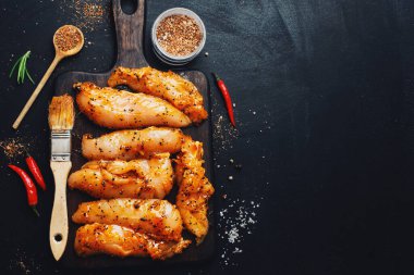 Koyu arka planda marine edilmiş çiğ tavuk göğsü ve pişirmeye hazır baharatlar.. 