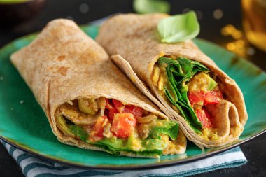 Tabakta ıspanaklı, domatesli ve avokadolu taze vejetaryen dürüm.. 