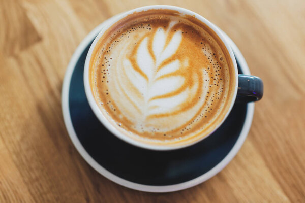 Tasty fresh cappuccino in cup on wooden table. Closeup