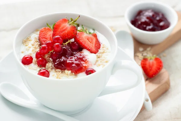 Haferflocken und Früchte in weißer Tasse mit Löffel auf Holzbrett zum Frühstück — Stockfoto