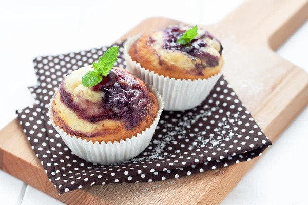 Muffin con marmellata di mirtilli su tessuto a polka su tavola di legno — Foto Stock