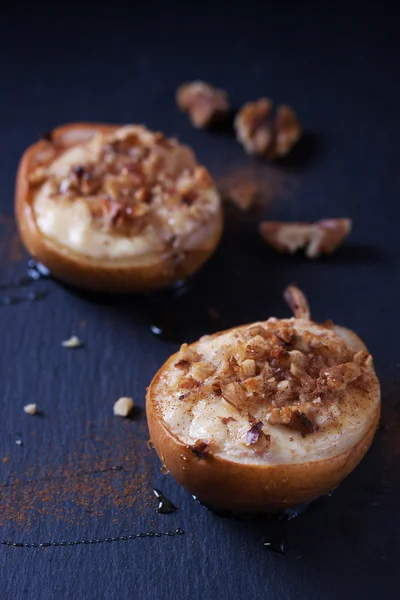 Baked pears with cottage cheese, honey and walnuts on dark background