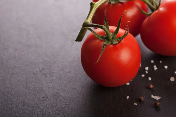 Pomodori freschi su sfondo di pietra nera — Foto Stock