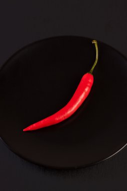 Siyah arka plan üzerine siyah plaka üzerinde kırmızı biber