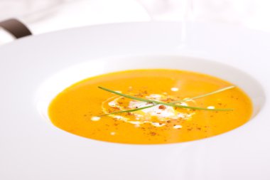 Kabak, havuç, kırmızı biber ve krem beyaz arka plan üzerinde beyaz kase sebze çorbası