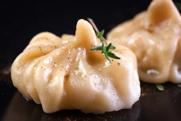 Oriental dumplings with thymine on a dark ceramic plate — Stock Photo, Image