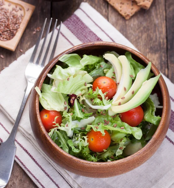 Салат з салатом, помідорами, насінням льону та авокадо в дерев'яній мисці . — стокове фото