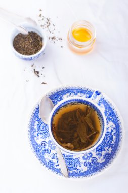 Bal bir arka plan üzerinde mavi bir fincan yeşil çay