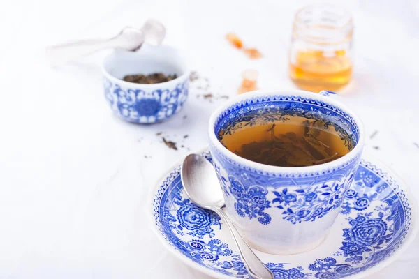 Green tea in a blue cup with honey on a white background — Stock Photo, Image