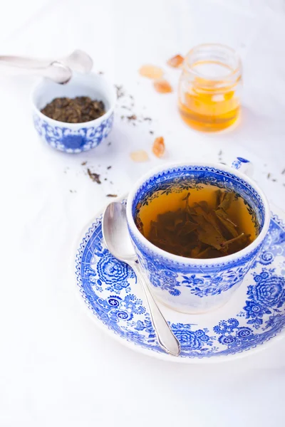 Grönt te i en blå kopp med honung på en vit bakgrund — Stockfoto