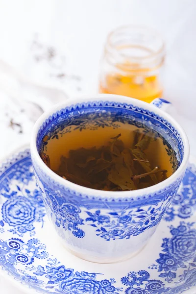 Green tea in a blue cup with honey on a white background — Stock Photo, Image