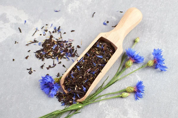 Black tea mix with dried cornflower petals and thyme in wooden scoop. Herbal tea. Healthy lifestyle concept.