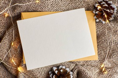 Arka planda çam ağacı konisi ve çelenk içeren tebrik kartı modeli. Fotokopi alanı olan düz bir Noel.