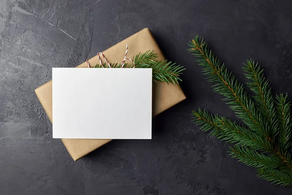 Koyu arkaplanda noel ağacı dalı ve hediye kutusu olan tebrik kartı modeli. Noel ve Yeni Yıl modeli, üst görünüm, kopyalama alanı.
