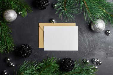 Çam ağacı dalları ve koyu arkaplanda noel süslemeleri olan tebrik kartı modeli. Üst görünüm, alanı kopyala.