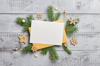 Boş tebrik kartı olan bir Noel modeli, ahşap arka planda şenlikli ağaç dalları. Fotokopi alanı olan düz bir Noel.