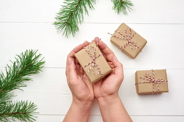 Vrouwelijke Handen Met Kerst Geschenkdoos Witte Houten Achtergrond Met Dennenbomen — Stockfoto
