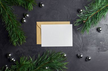 Çam ağacı dalları ve koyu arkaplanda noel süslemeleri olan tebrik kartı modeli. Üst görünüm, alanı kopyala.