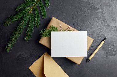 Hediye kutusu ve koyu arkaplanda köknar dalı olan bir Noel kartı modeli. Kış tatilleri kompozisyonu, üst görünüm, düz döşeme, kopyalama alanı.