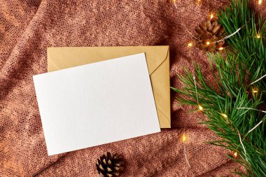 Arka planda çam ağacı dalı ve çelenk olan tebrik kartı modeli. Zarflı boş kart. Fotokopi alanı olan düz bir Noel.