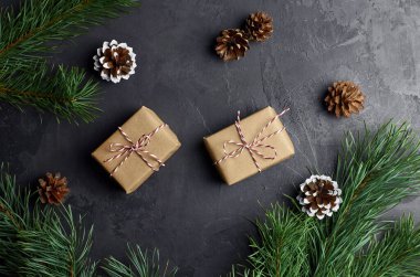 Noel dairesi, hediye kutularıyla, çam ağacı dallarıyla ve koyu arkaplanda kozalaklarla yatıyordu. Noel düzlüğü, üst manzara.