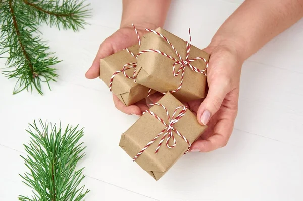 Vrouwelijke Handen Met Kerst Geschenkdozen Witte Houten Achtergrond Met Dennenbomen — Stockfoto