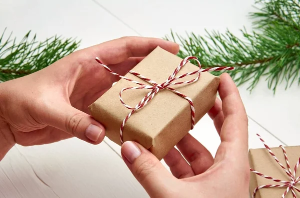 Vrouwelijke Handen Met Kerst Geschenkdoos Witte Houten Achtergrond Met Dennenbomen — Stockfoto