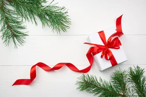 Kerstgeschenkdoos Met Rood Lint Dennenboomtakken Witte Houten Ondergrond — Stockfoto